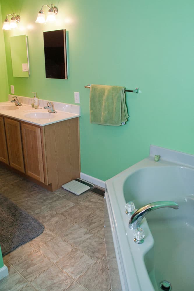 Modern bathroom with aqua walls, wood vanity, and corner bathtub