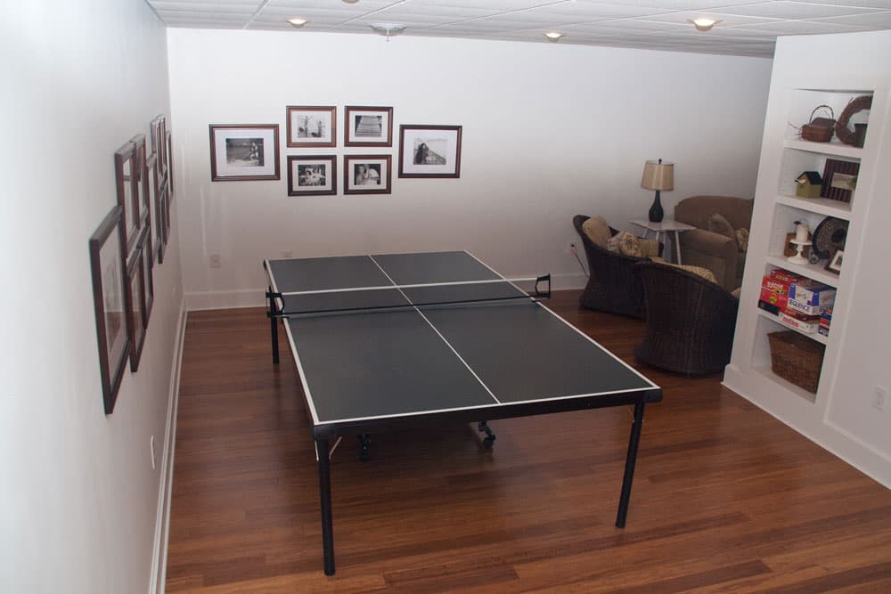 Finished basement recreation room with ping pong table and built-in shelving