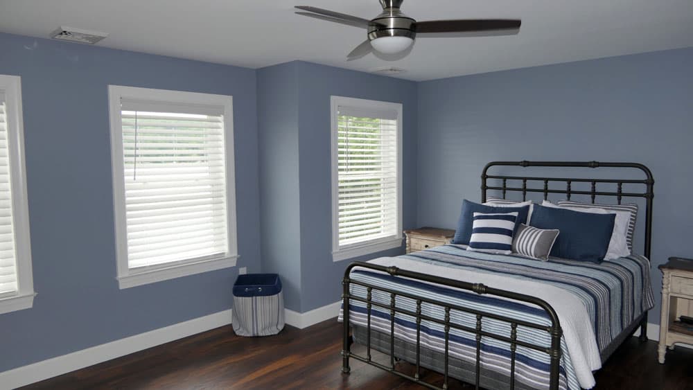 Blue bedroom with dark metal bed frame, striped bedding, and ceiling fan