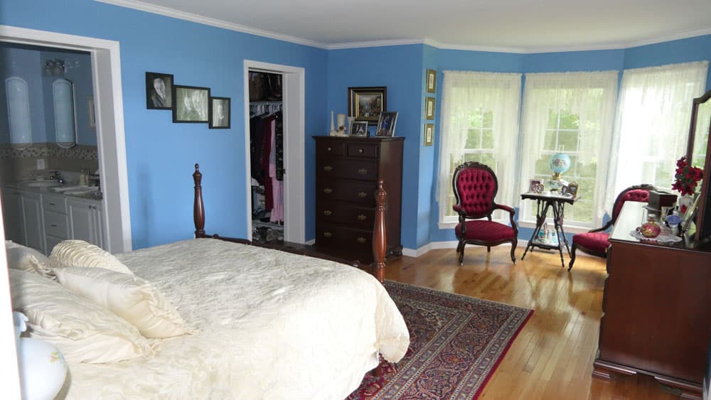 Spacious bedroom with blue walls, hardwood floors, and attached bathroom