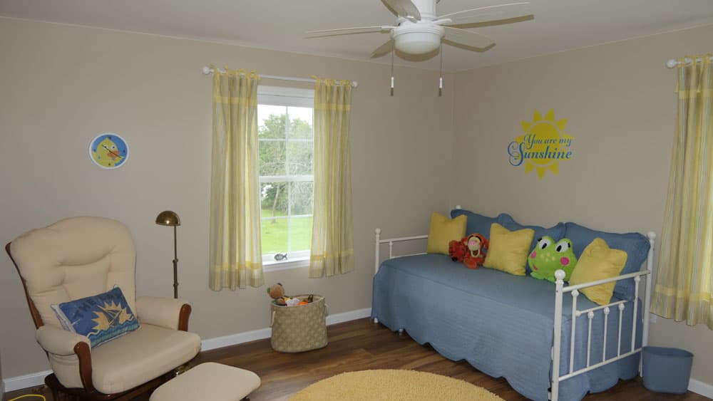 Child's bedroom with white daybed, yellow accents, and 'You are my Sunshine' wall decal