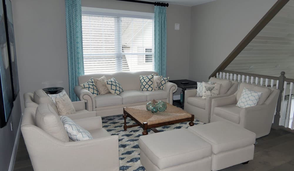 Modern living room with turquoise accents, white furniture, and staircase railing