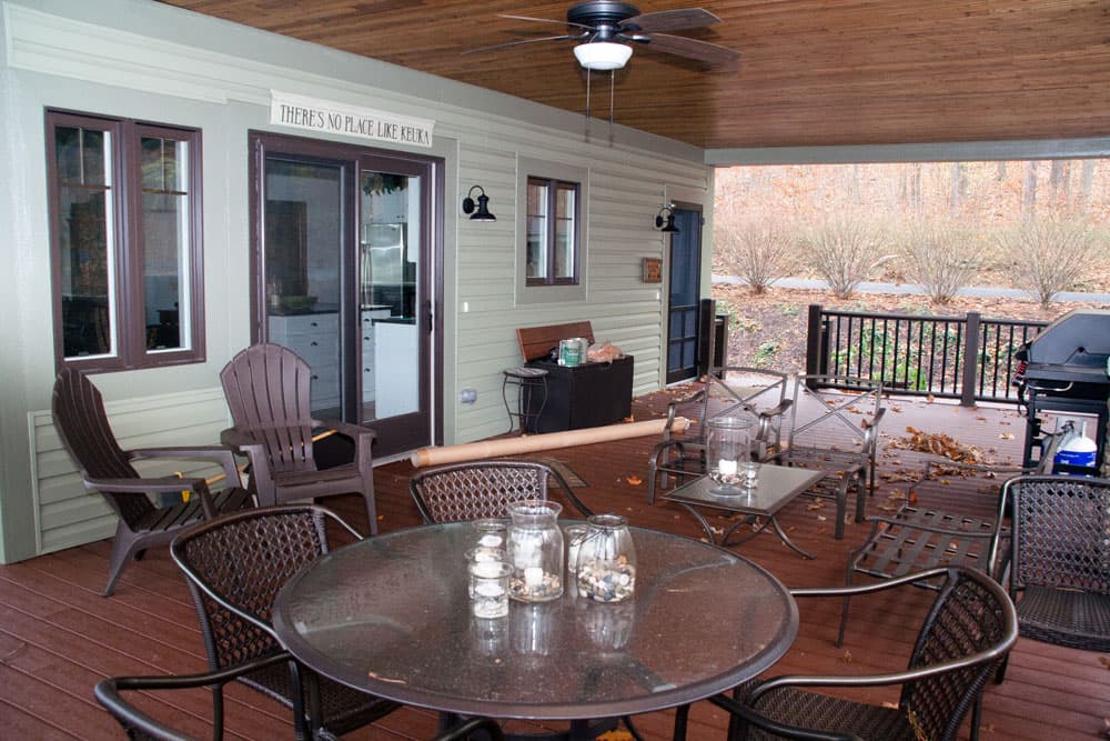 Covered deck with dining tables, Adirondack chairs, ceiling fan, and wood planking