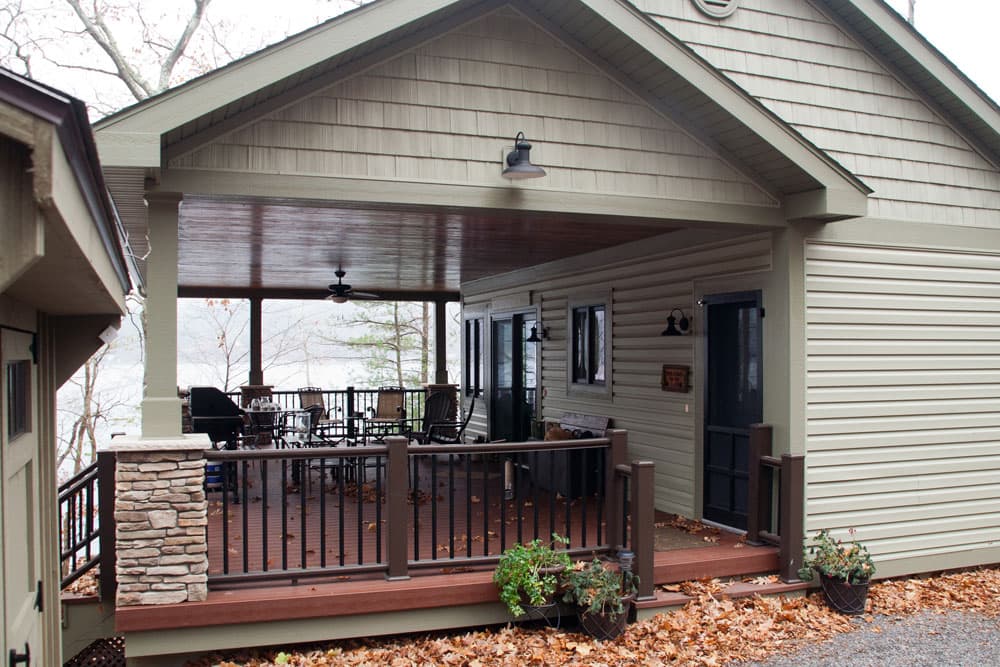 Covered deck with wood railings, ceiling fan, and outdoor seating area