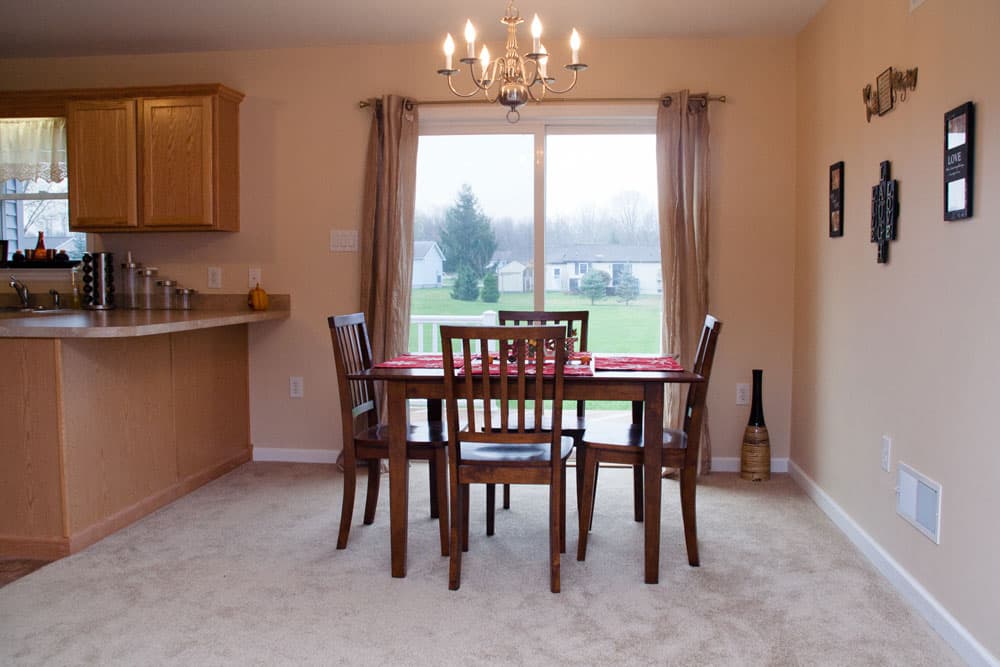 Dining room with wood table and chairs overlooking backyard through large window