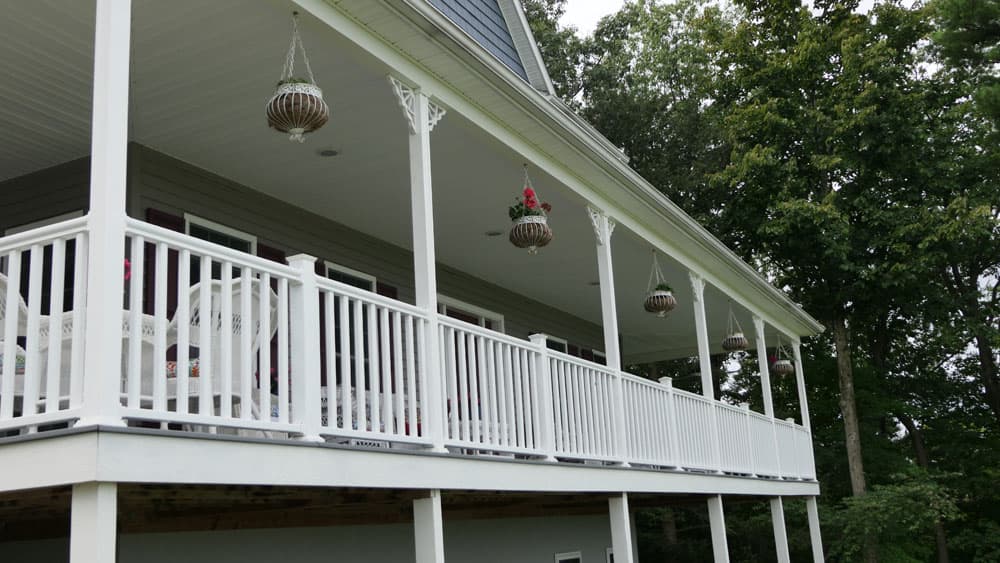 White railing deck with decorative hanging planters under covered porch