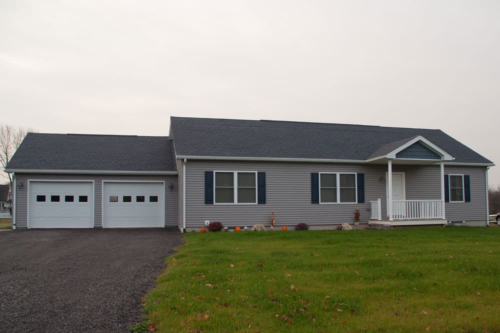 Gray ranch-style modular home with white garage and front porch