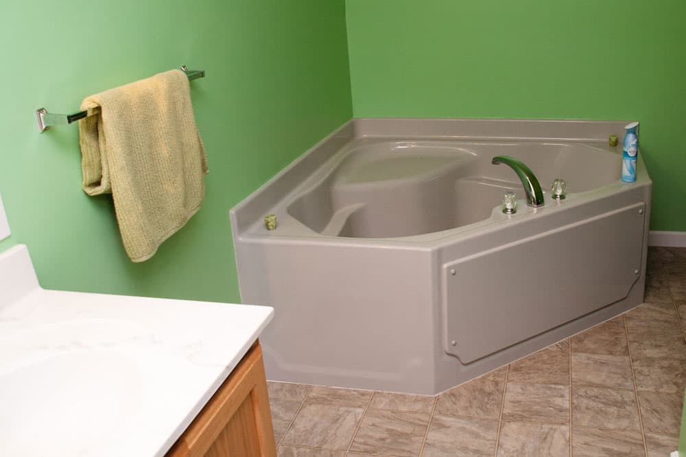 Gray walk-in bathtub with door panel in bathroom with green walls