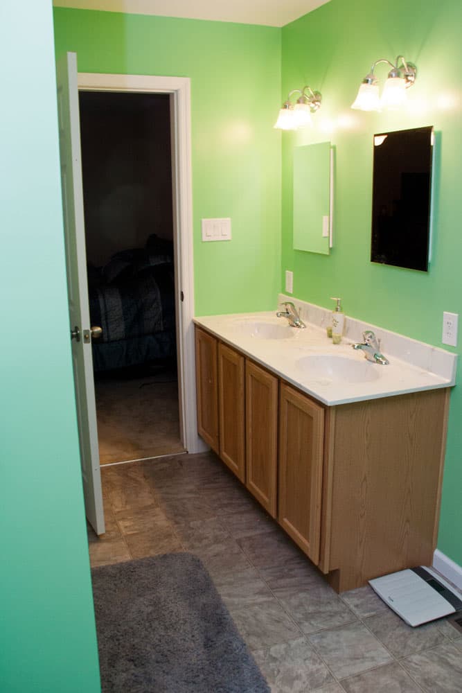 Bathroom with lime green walls, wood vanity with dual sinks, and white countertop