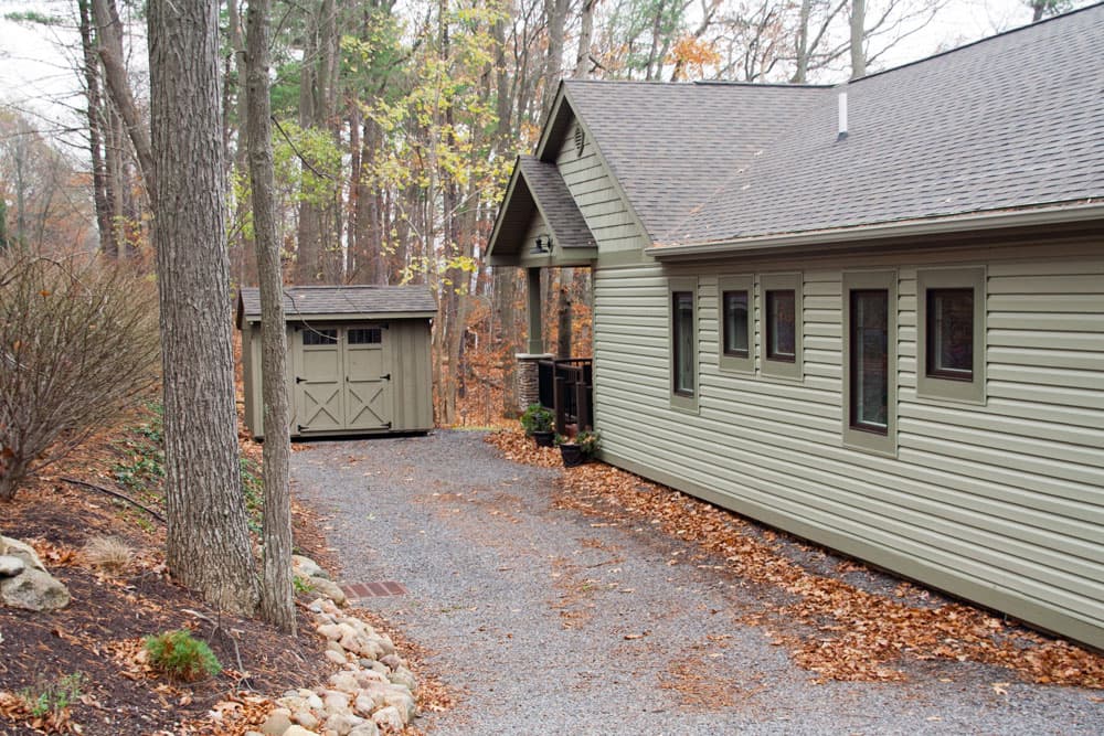 Green horizontal siding on house with gray shingle roof and detached garage