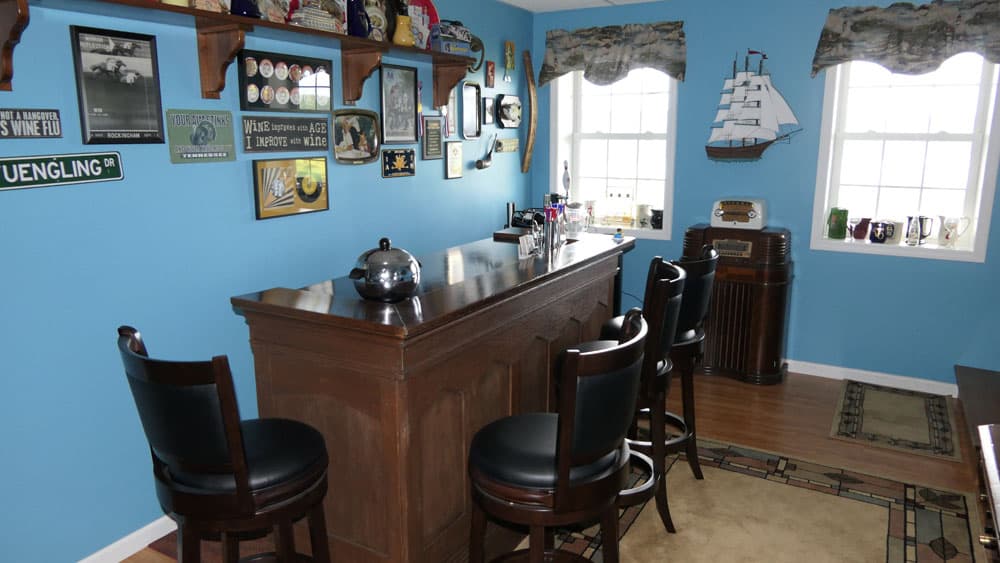 Home bar with blue walls, nautical decor, dark wood counter, and leather swivel stools