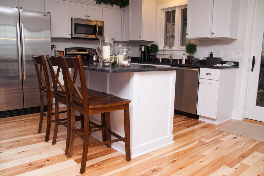 Modern kitchen with white cabinets, granite island, and natural hardwood flooring