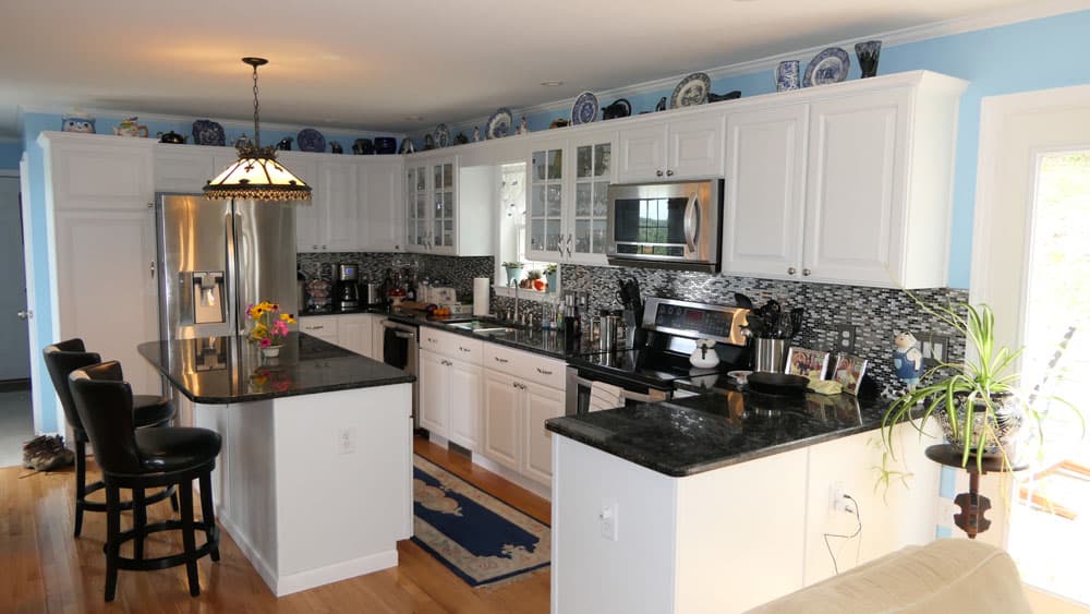 Modern kitchen with white cabinets, black granite countertops, and stainless steel appliances