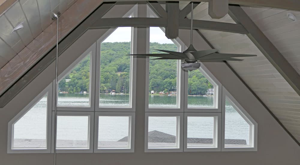 Vaulted boathouse interior with exposed beams and large windows overlooking lake