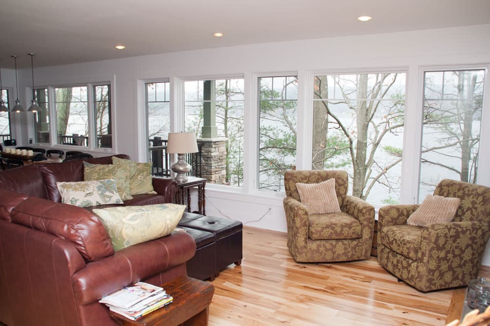 Open living room with hardwood floors and large windows overlooking lake