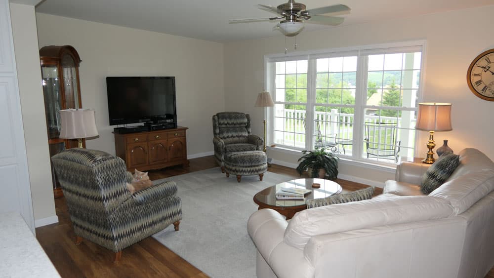 Living room with patterned armchairs, leather sofa, and white French doors to deck