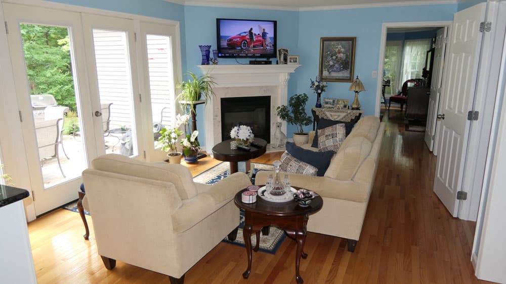 Living room with blue walls, beige furniture, fireplace, and TV above mantel