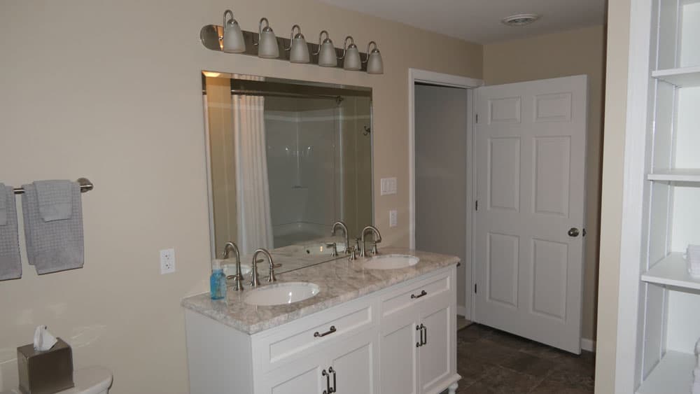Master bathroom with double sink vanity, marble countertop, and white cabinetry