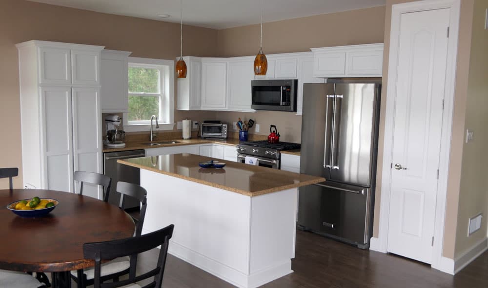 Modern kitchen with white cabinets, brown countertops, and stainless steel appliances