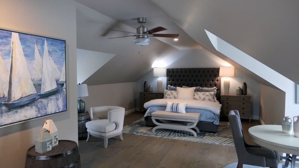 Loft bedroom with sailboat painting, tufted headboard, and skylight