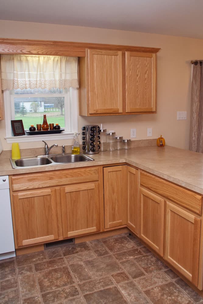 Kitchen corner with oak cabinets, beige countertops, and stainless steel sink