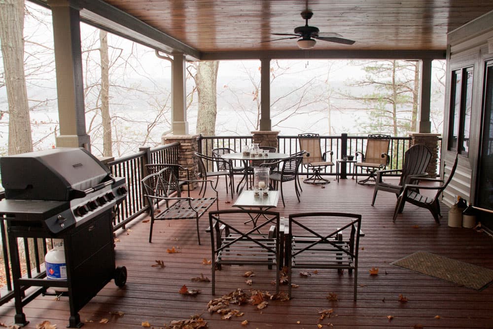 Covered deck with wood ceiling, ceiling fan, and outdoor furniture overlooking foggy woods