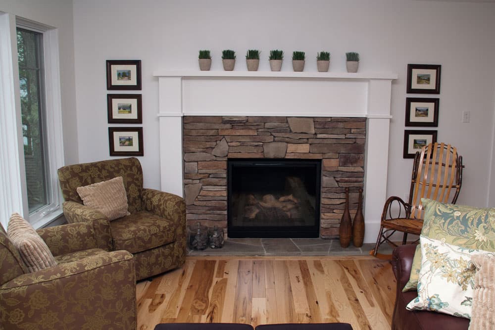 Living room with stacked stone fireplace and white mantel