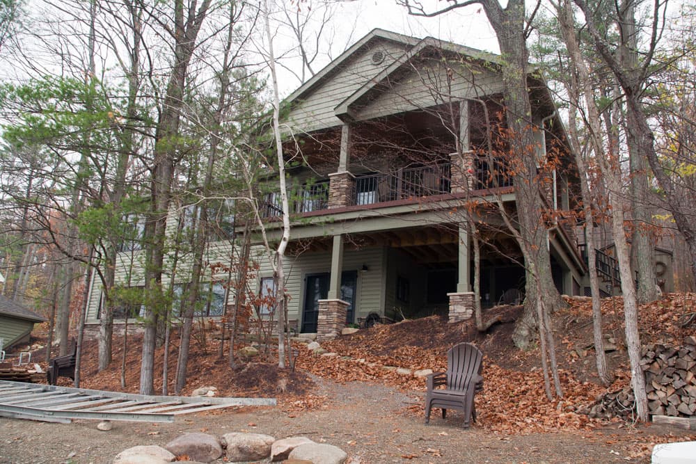 Two-story home with covered porch and upper deck nestled in wooded hillside