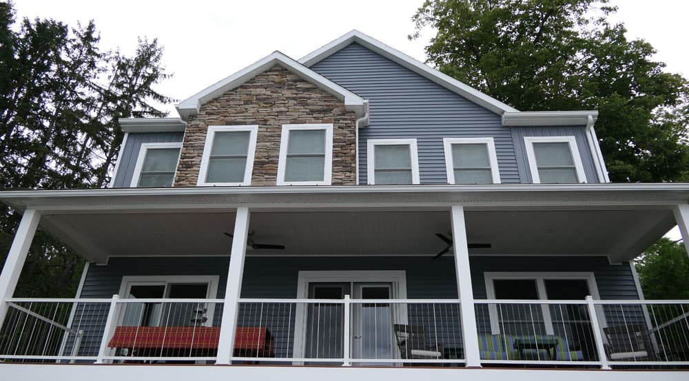 Modern two-story home with blue siding, stone accent, and covered deck