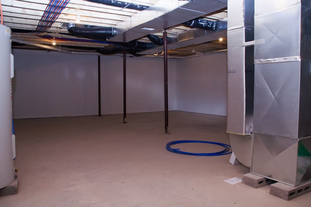 Unfinished basement with exposed ceiling ducts, support posts, and HVAC system