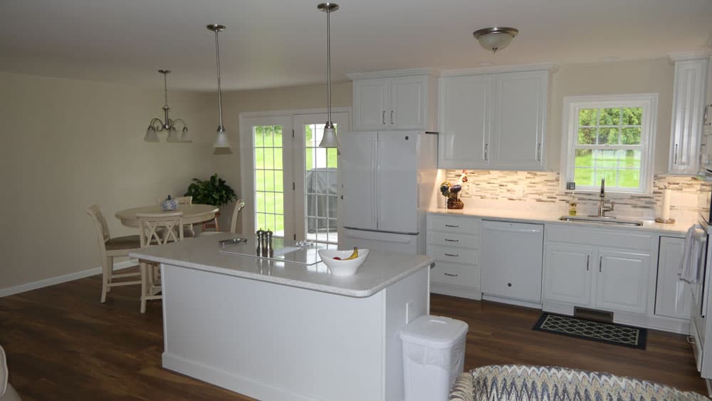 Modern white kitchen with island, pendant lighting, and wood floors