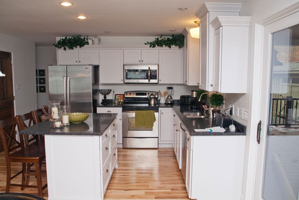 Modern kitchen with white cabinets, gray countertops, and stainless steel appliances