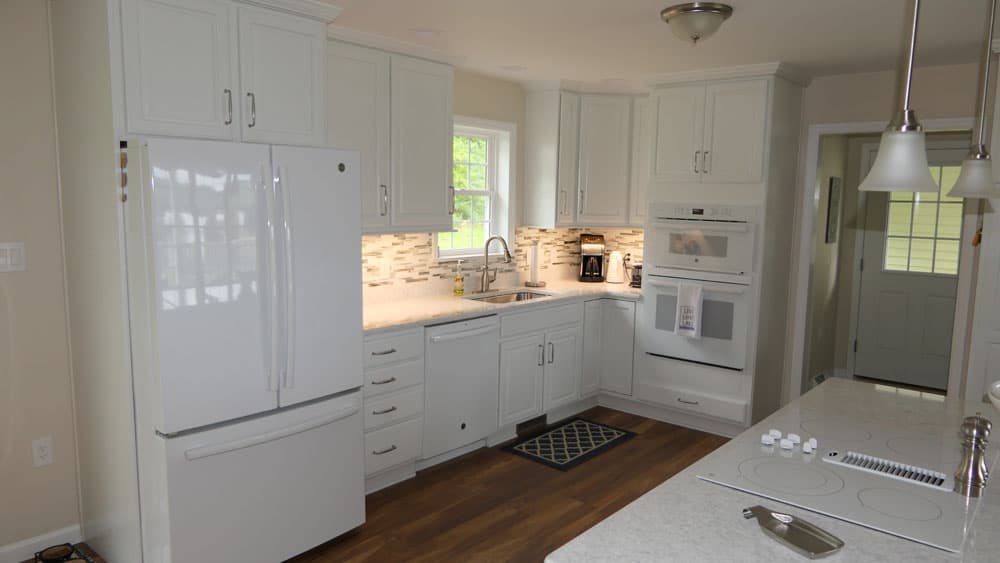 Modern white kitchen with custom cabinetry, tile backsplash, and white appliances